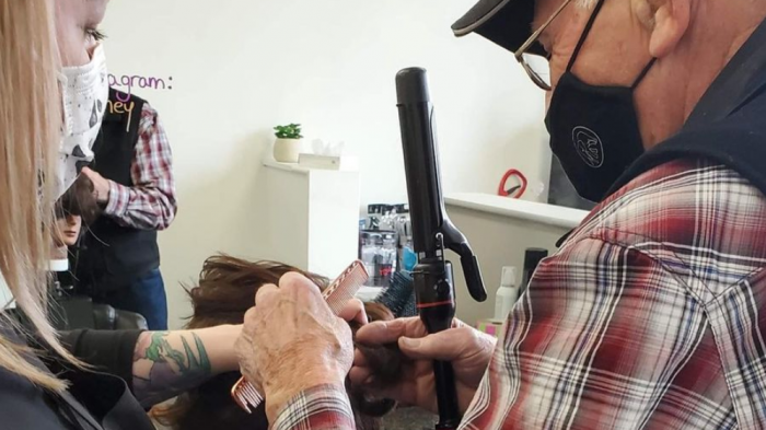Adulto mayor acude a una peluquería para aprender a rizarle el pelo a su esposa